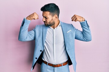 Young hispanic businessman wearing business jacket showing arms muscles smiling proud. fitness concept.