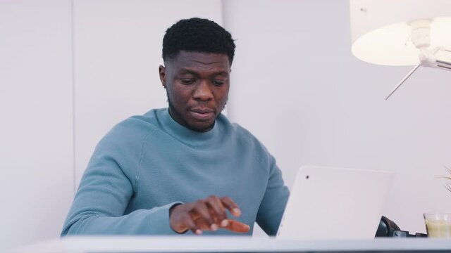 African American black man sitting at the table in front of a laptop - Stressed out using smartphone. High quality 4k footage