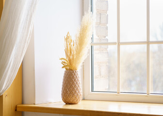 Reed plume stem, vase with dry flower on window, dried pampas grass. Decorative flower arrangement...