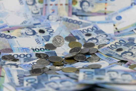 A pile of one thousand Philippines banknotes and coins