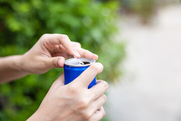 Closeup woman hand open cola can with nature background.
