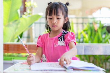 Asian girls enjoy homework. Asian girl does homework in the classroom. girl kid activity in classroom.