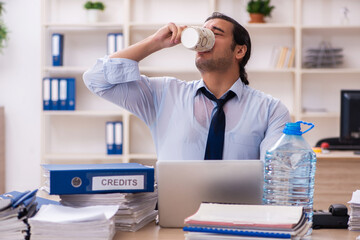 Young male employee being thirsty in the office