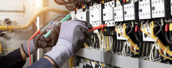 Electrician engineer tests electrical installations and wires on relay protection system. Adjustment of scheme of automation and control of electrical equipment.