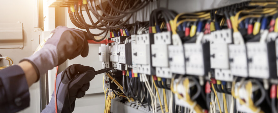 Electrician engineer tests electrical installations and wires on relay protection system. Adjustment of scheme of automation and control of electrical equipment.