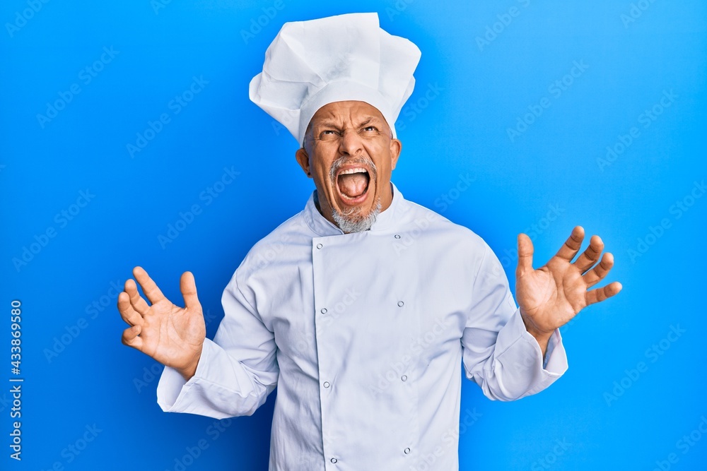 Sticker Middle age grey-haired man wearing professional cook uniform and hat crazy and mad shouting and yelling with aggressive expression and arms raised. frustration concept.