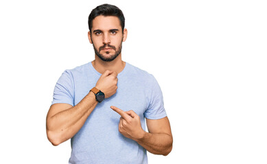 Young hispanic man wearing casual clothes in hurry pointing to watch time, impatience, looking at...