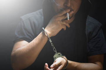 Young man of prisoner in handcuffs smoking a cigarette