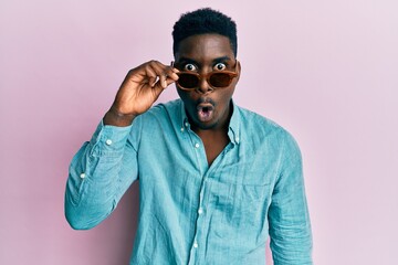 Handsome business black man wearing stylish sunglasses scared and amazed with open mouth for surprise, disbelief face