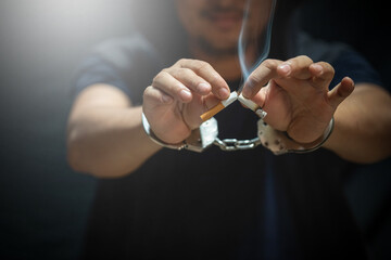 Young man of prisoner in handcuffs breaking cigarette. Quitting smoking habit.