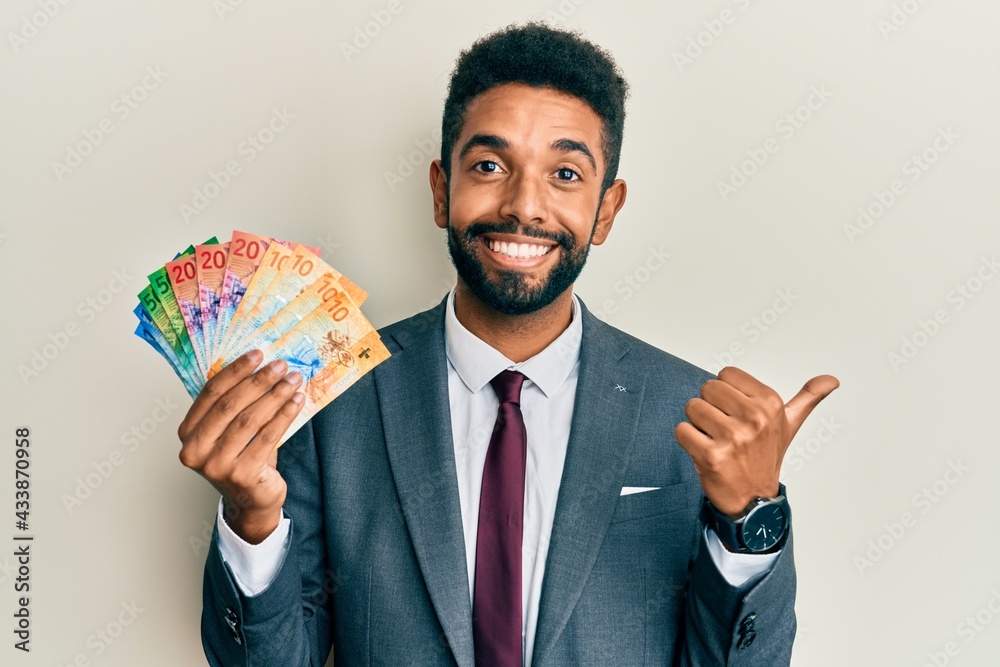 Canvas Prints Handsome hispanic business man with beard holding swiss franc banknotes pointing thumb up to the side smiling happy with open mouth