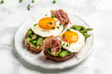 Grilled Toast witch Asparagus, Poached egg, bacon jamon, ham, prosciutto on white background. Food recipe background. Close up