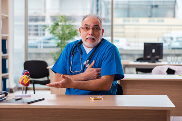 Old male doctor cardiologist working in the clinic
