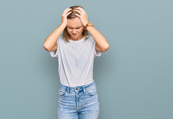 Beautiful young blonde woman wearing casual white t shirt suffering from headache desperate and stressed because pain and migraine. hands on head.