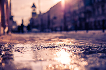 Streets in the late autumn, people walking on the street. Close up view from the level of the puddle on the sidewalk