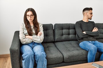 Young hispanic couple angry sitting on the sofa in silence at home.