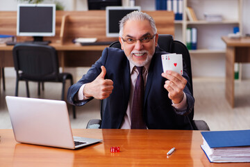 Old male employee playing cards at workplace