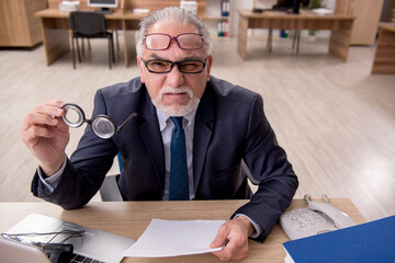 Old male employee auditor wearing many glasses at workplace