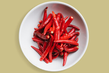 Bright red chili in a cup on a pastel yellow background.