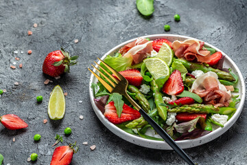 Vegetarian vegetable salad of fresh green asparagus, strawberry, rocket and cottage cheese. Diet banner, menu recipe place for text, top view