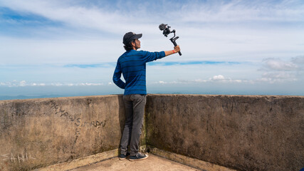 Young asian blogger or vlogger looking at camera and talking on video shooting with technology....