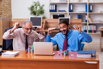 Two male employees playing cards at workplace