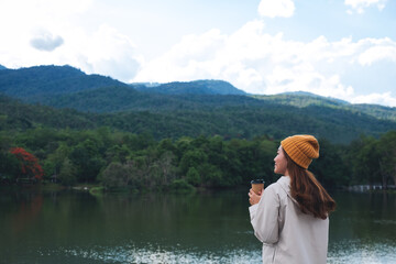 A young asian woman drinking coffee while traveling mountains and the lake