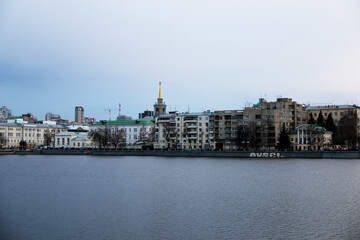 View from the embankment to the evening city. City landscape on the river bank