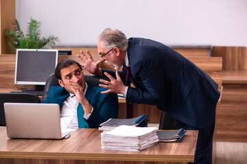 Old male employer and young male assistant in bullying concept