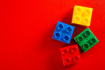 Color plastic building blocks on red background