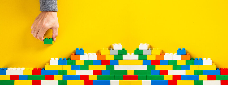 hand building up a wall by stacking up plastic block