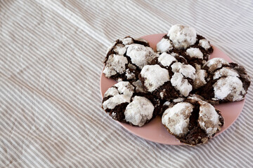 Homemade Chocolate Crinkle Cookies on a pink plate, side view. Copy space.