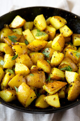 Homemade Roasted Potatoes with Mustard Seeds in a cast-iron pan, side view. Close-up.