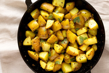 Homemade Roasted Potatoes with Mustard Seeds in a cast-iron pan, top view. Flat lay, overhead, from above.