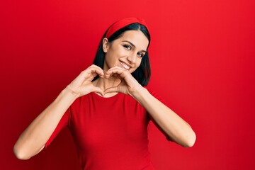 Young hispanic woman wearing casual clothes smiling in love doing heart symbol shape with hands. romantic concept.