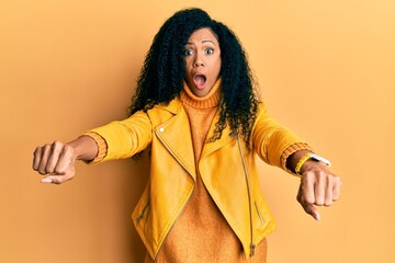 Middle age african american woman doing motorcycle symbol with hands afraid and shocked with surprise and amazed expression, fear and excited face.