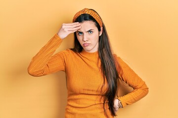 Young brunette teenager wearing casual yellow sweater worried and stressed about a problem with hand on forehead, nervous and anxious for crisis