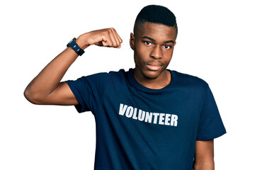 Young african american man wearing volunteer t shirt strong person showing arm muscle, confident and proud of power