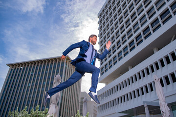 Business man running and jumping in a city street.