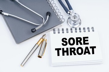 On the table are a stethoscope, a pen and a notebook with the inscription - SORE THROAT