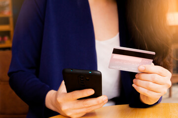 The woman is using the phone to enter her credit card number to pay online,