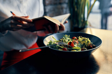 notepad with a pen in hand and salad in a plate restaurant cafe inscription