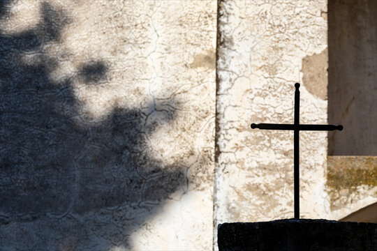 Antico crocefisso di metallo con sfondo il muro della chiesa.