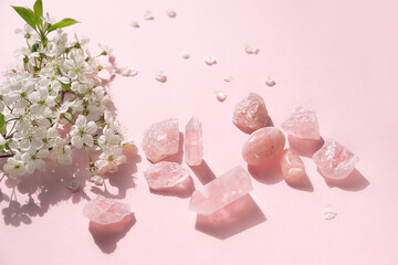 Rose quartz minerals set and white flowers. spa, relax concept. Healing pink quartz gemstones for...