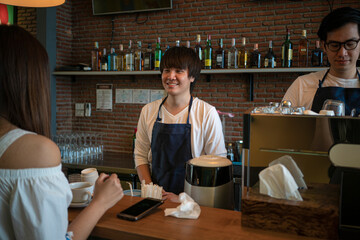 Asian barista making coffee with coffee machine and serving a cup of cappuccino in coffee shop. small business owner and restaurant concept