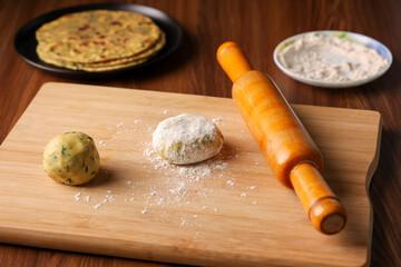 Wooden roller whole wheat dough preparing Palak paratha spinach paratha parantha chapati Indian flatbread roti made from spinach with yogurt mint dip, North Indian breakfast food Delhi India