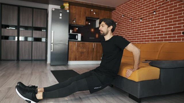 Man athletic doing push up leaning on sofa at home