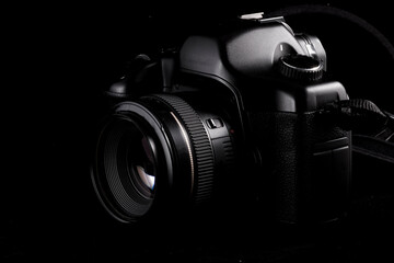 Fototapeta na wymiar Professional modern DSLR camera low key image - Modern DSLR camera with a lens on