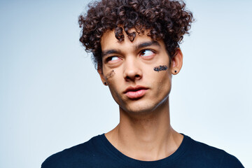 guy with curly hair applies a black mask on his face cosmetology