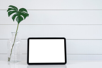 Mockup blank screen tablet and houseplant on white top table with copy space.